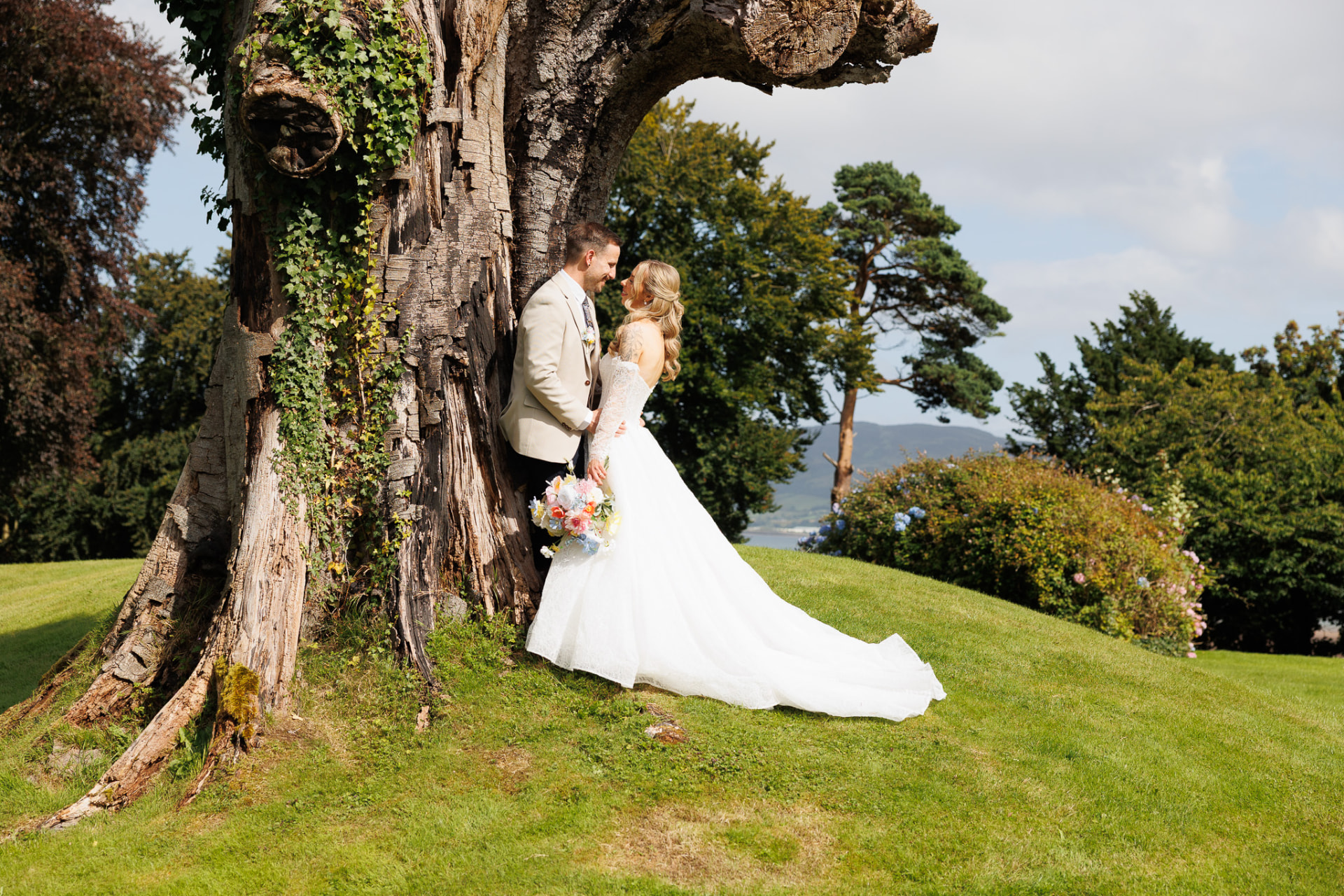 Bride and groom beside an ancient tree with the lough behind